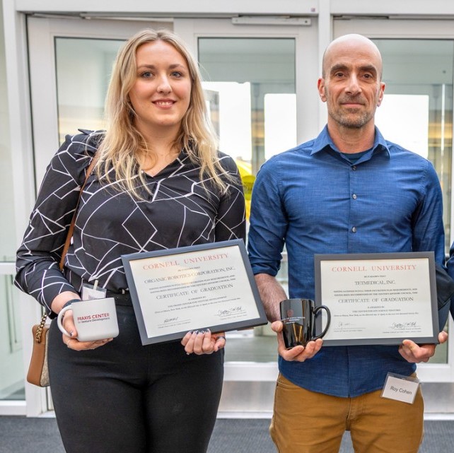 Two people standing and holding certificates